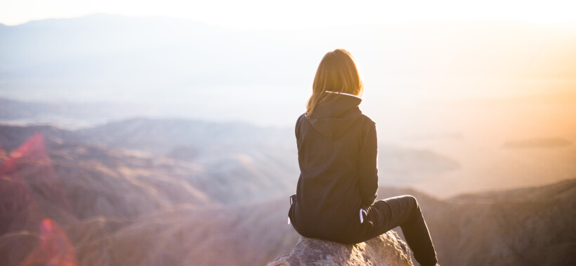 A woman looking out over the hills at sunrise