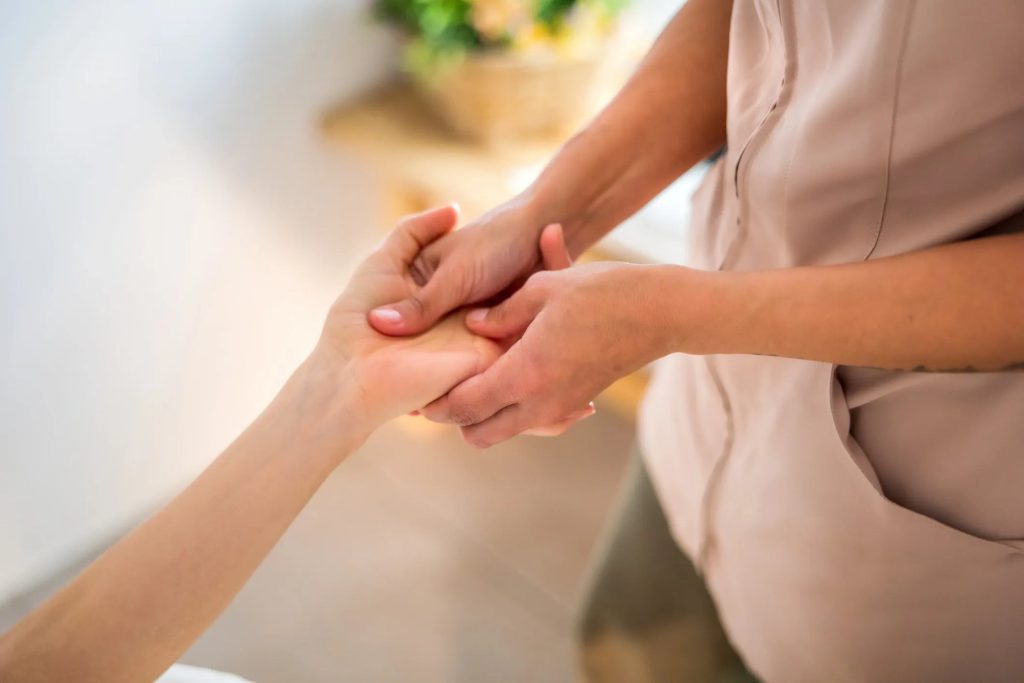 A practitioner pressing points on a patient’s hand